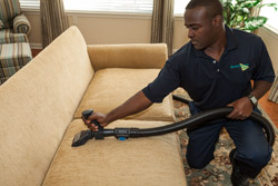 A ServiceMaster technician using specialty equipment to clean an upholstered couch